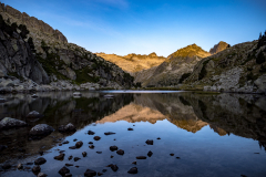 Reflejo de montañas sobre un lago con piedras