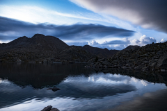 Reflejos en las aguas de un lago de curiosas nubes y montañas